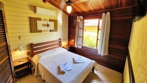 A wooden-paneled room with a bed, a ceiling fan, a window with curtains, and a wall-mounted air conditioning unit. - Vale do Sonho Hotel e Eventos (Guararema)