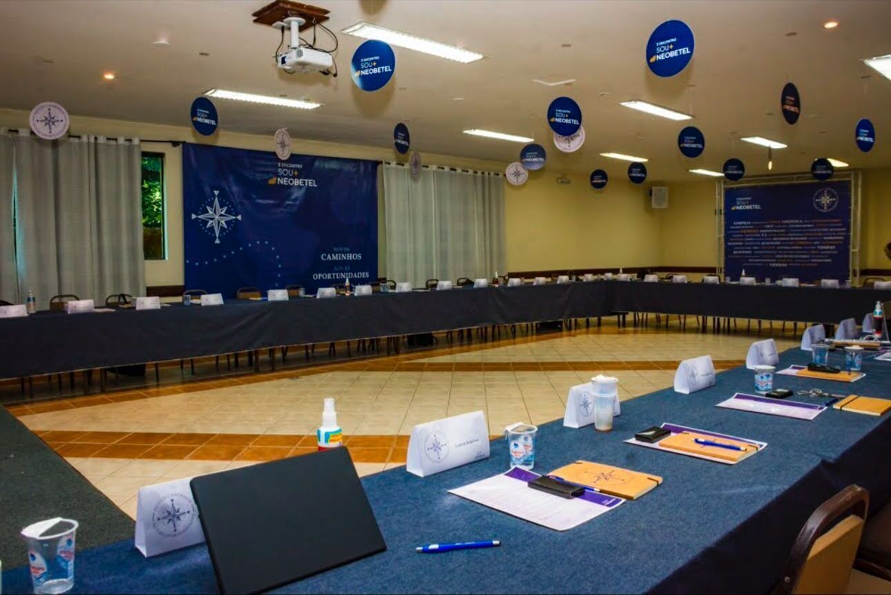 Un salón de conferencias con una larga mesa, sillas, tarjetas de identificación y un banderín.