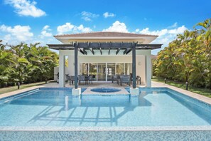 A swimming pool with a covered patio area, surrounded by lush greenery. - Golf Villa in Bavaro - Pool, Jacuzzi, Staff (Punta Cana)