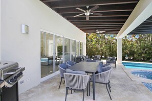 An outdoor patio with a pool, a grill, and a seating area with chairs and a table. - Golf Villa in Bavaro - Pool, Jacuzzi, Staff (Punta Cana)