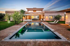 A modern house with a swimming pool, outdoor seating, and a well-maintained garden.