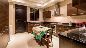 A modern kitchen with dark wood cabinets, a central island with a glass top, and a dining area with a table set for two. - Villa Ziram - Four Bedroom Villa, Sleeps 8 (Sidi Youssef Ben Ali)