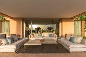 A modern outdoor living area with two sofas, a coffee table, and a glass door leading to a patio.