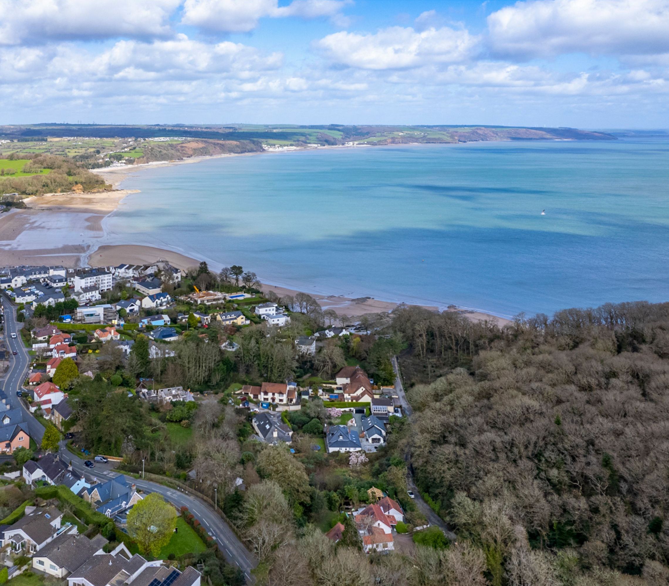 Luchtbeeld van een kustgebied met woningen, wegen en een strand.