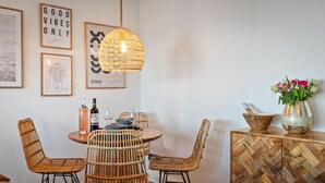 A dining area with a round table, wicker chairs, and a hanging light fixture. - Beach Retreat - Sea Views, Parking, Beach Access (Saundersfoot)