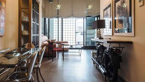 Un salon moderne avec une table à manger en verre, un canapé en cuir et une moto exposée.