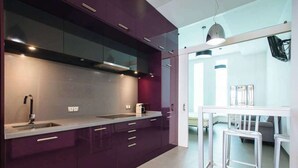 Une cuisine moderne avec des meubles de couleur sombre, des plans de travail en acier inoxydable et un four encastré.