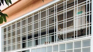 Une façade d’immeuble avec une grille de fenêtres et une porte recouverte de graffitis.