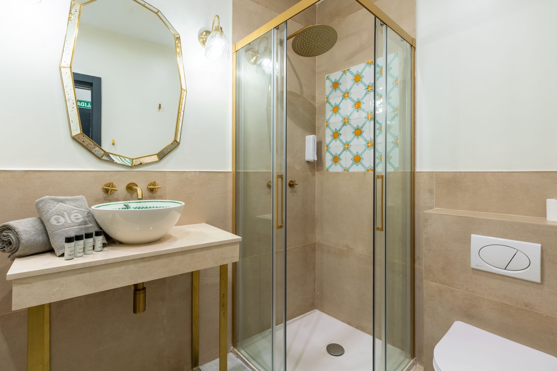 A bathroom with a glass-enclosed shower, a sink with a white basin, and a mirror with a gold frame.