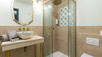 A bathroom with a glass-enclosed shower, a sink with a white basin, and a mirror with a gold frame.