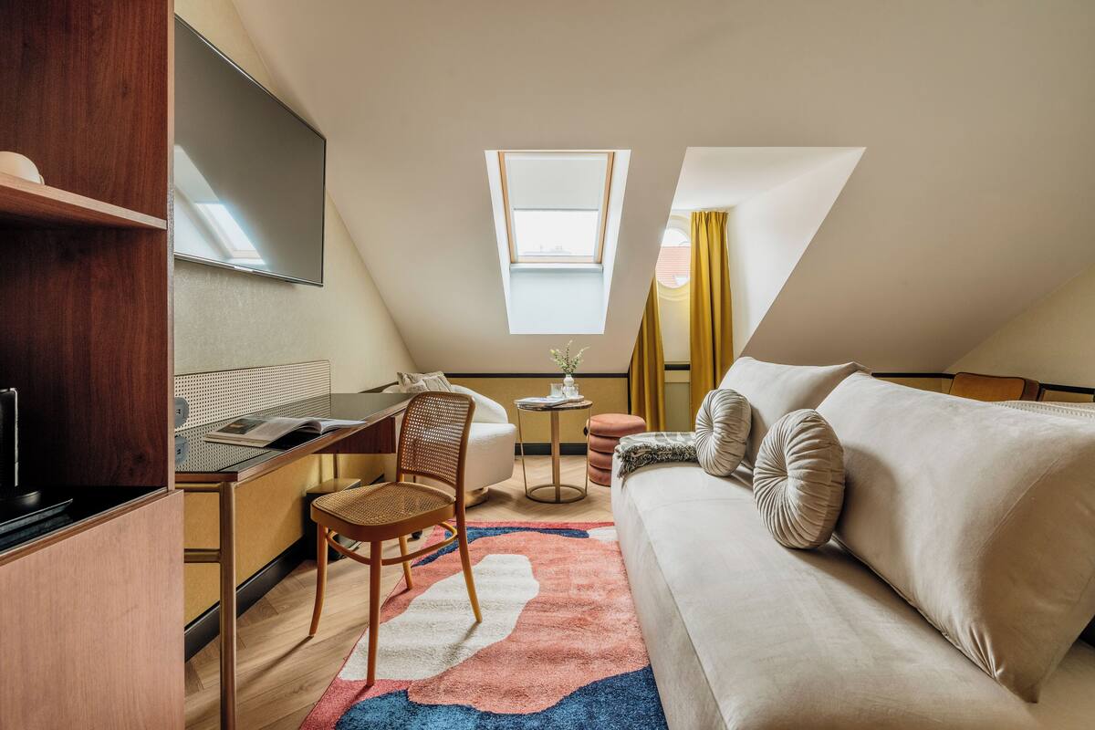 Une pièce compacte et moderne, dotée d’une kitchenette, d’un coin repas, d’un canapé et d’une petite table agrémentée d’un vase.