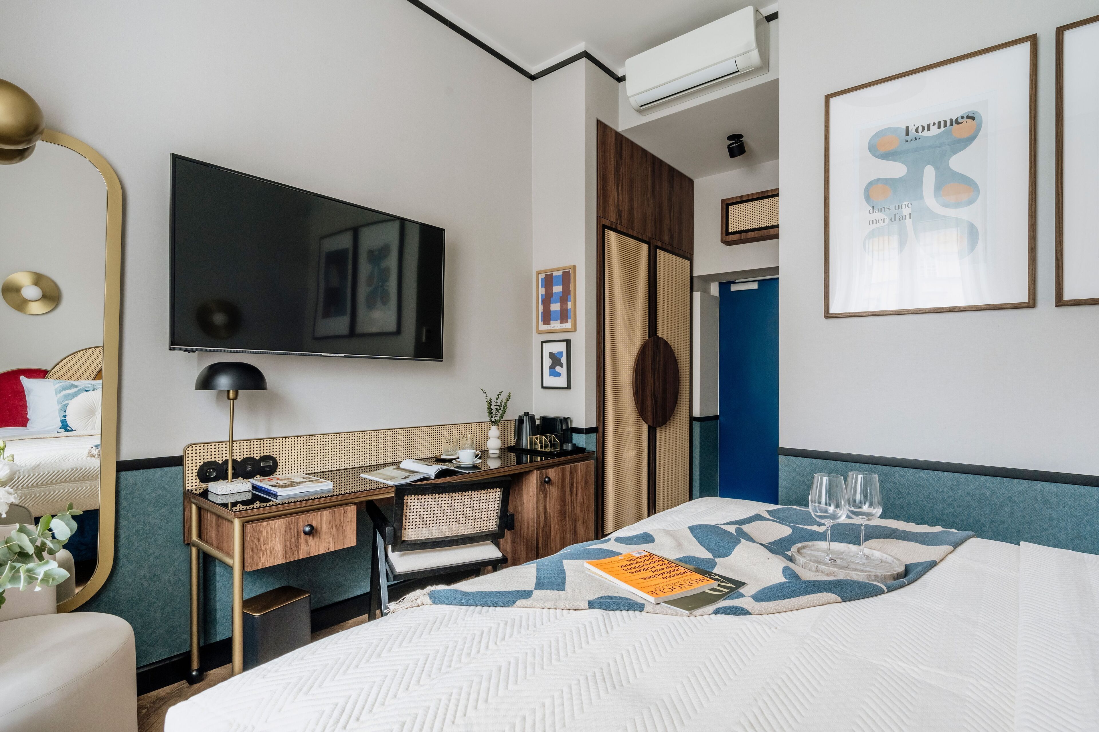 A hotel room with a bed, a desk, a chair, a TV, and a wardrobe.
