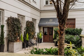 A boutique with a dark awning and a wooden door, surrounded by potted plants and outdoor seating. - Colette by StayLab (Warsaw)