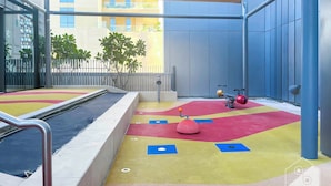 A children's play area with colorful flooring, a small pool, and exercise equipment. - Elegant 2B at Boulevard Pointburj & Fountain View (Dubai)