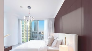 A modern hotel room with a large bed, a nightstand with a lamp, and a view of tall buildings. - Elegant 2B at Boulevard Pointburj & Fountain View (Dubai)
