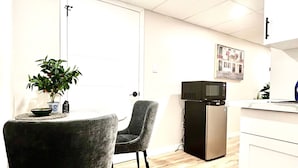 A compact kitchen with a refrigerator, microwave, and a small dining area with two chairs and a table.