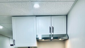 A kitchen with white cabinets, a stainless steel range hood, a coffee maker, and a paper towel holder.