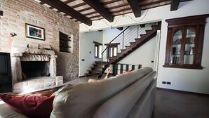 Una sala de estar con chimenea, un sofá, una escalera y un aparador de madera.
