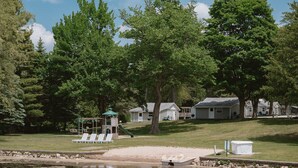A lakeside property with a small dock, a playground, and several houses. - Brookside Cottages and Resort Driftwood Cottage (Grawn)