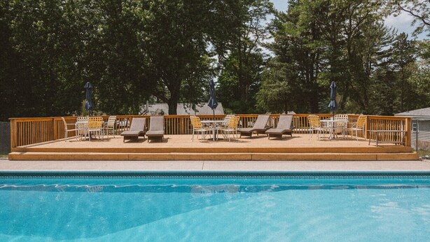 A swimming pool with lounge chairs and umbrellas. - Brookside Cottages and Resort Freedom Cottage (Grawn)