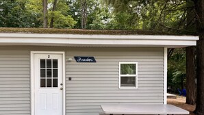 A small cabin with a white door, a sign reading "Freedom", and a picnic table in front. - Brookside Cottages and Resort Freedom Cottage (Grawn)