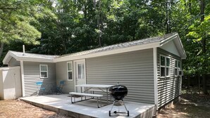 A single-story house with a covered patio, a barbecue grill, and a picnic table.