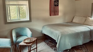 A cozy attic bedroom with a sloped ceiling, a bed, a chair, and a small table.