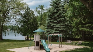 Ein Spielplatz mit Rutsche, Schaukeln und einer überdachten Spielkonstruktion.