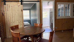 A dining area with a wooden table and chairs, a ceiling fan, and a view of the outdoors through a door. - Brookside Cottages and Resort Brookside Cottage (Grawn)