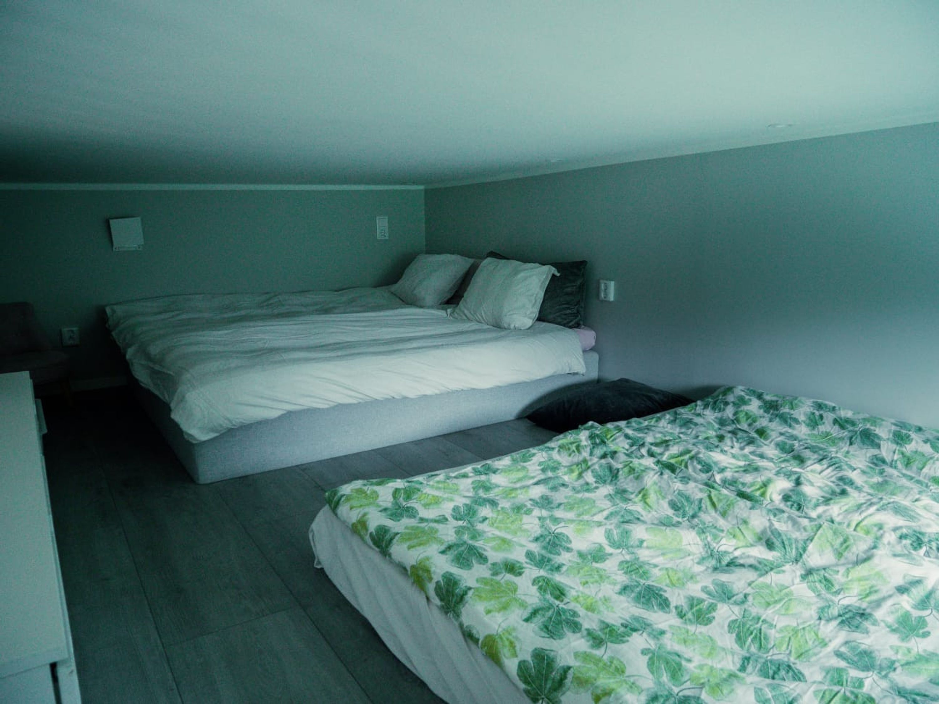 Quarto com duas camas, uma cômoda e uma mesa de cabeceira.
