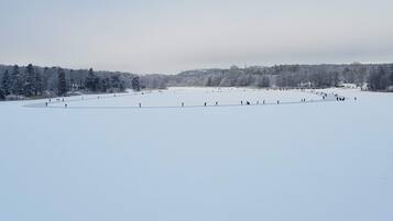 A large, open, snow-covered field with a few people scattered around.