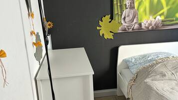 Ein Schlafzimmer mit Bett, Schreibtisch, Stehlampe und Wandbild.