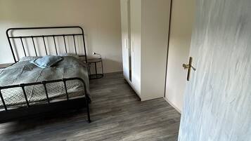 Ein Schlafzimmer mit einem Metallbettgestell, einem kleinen Nachttisch und einem Kleiderschrank.