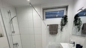A modern bathroom with a glass shower enclosure, a white sink, and a wooden floor. - Cozy vacation apartment directly at the highway entrance (Freudenberg)