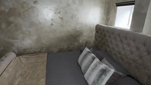 Une chambre à coucher avec un lit, une fenêtre et un mur à texture.