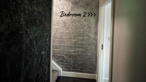 Un couloir mène à une pièce dont la porte est marquée « Chambre 2 ».