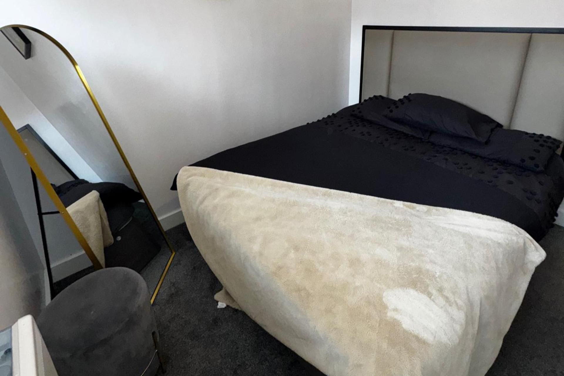 A bedroom with a bed, a headboard, a bedside table, and a chair.