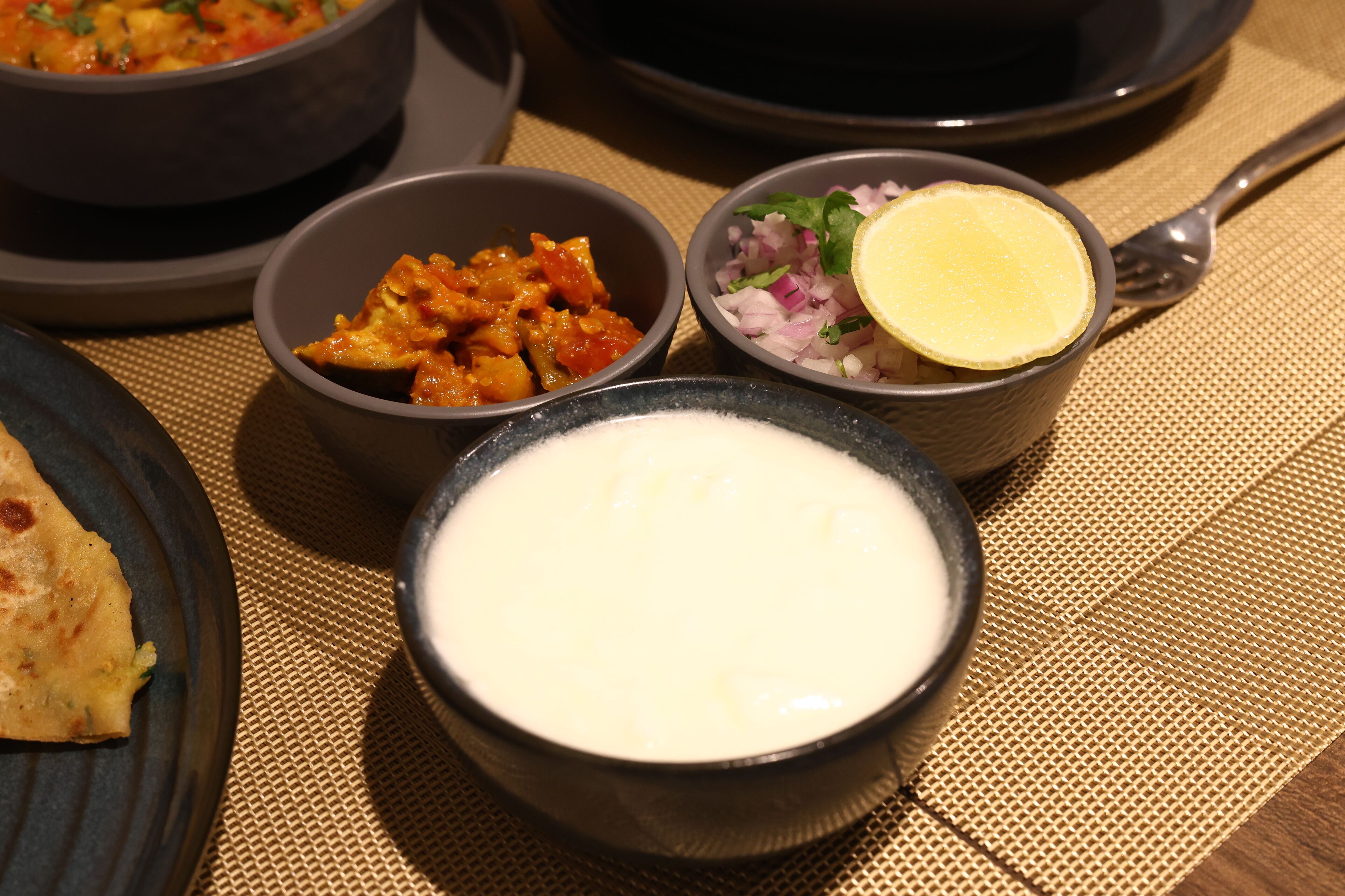 A table with various dishes including a bowl of white sauce, a bowl of mixed vegetables, and a bowl of curry.