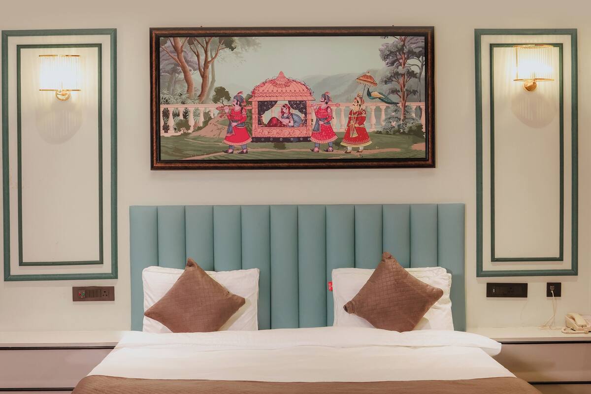 Una cama bien tendida con un cabecero tapizado color turquesa, dos almohadas y una colcha blanca.