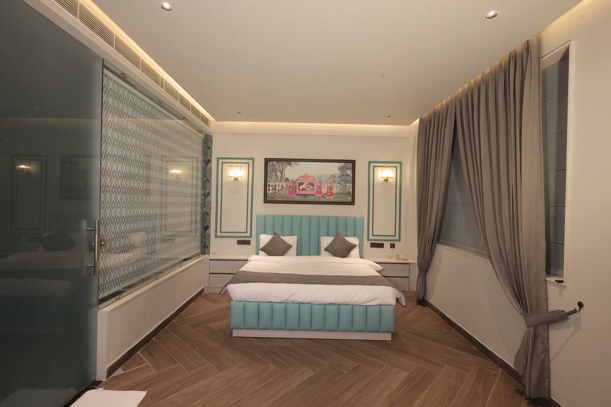 Un dormitorio moderno con una cama grande, un separador de vidrio y un cuadro en la pared.