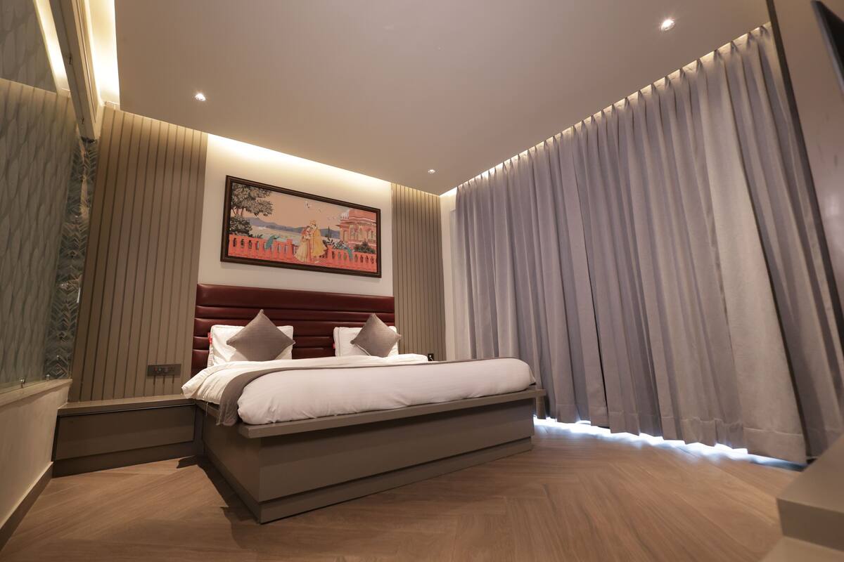Un dormitorio moderno con una cama grande, un cabecero con líneas verticales, un cuadro en la pared y una ventana con cortinas.