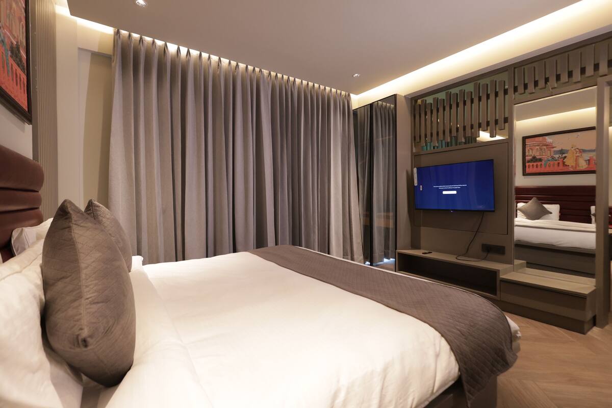 Una habitación de hotel moderna con una cama grande, un televisor de pantalla plana y un armario con puertas correderas.
