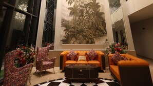 Un vestíbulo con una lámpara de araña grande, un mural decorativo en la pared y una zona de estar con arreglos florales.
