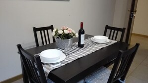 A dining table set with plates, a wine bottle, and a vase of flowers. - 01. Apartment (Signa)