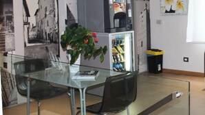 A modern room with a glass table, two chairs, a vending machine, and a trash bin. - 01. Apartment (Signa)