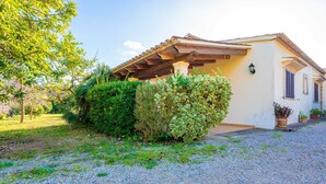 A house with a covered porch, a gravel driveway, and a well-maintained garden. - Ca Na Xisca Pollen a (Pollenca)