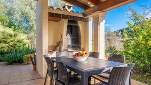 An outdoor patio with a table and chairs, a grill, and potted plants. - Ca Na Xisca Pollen a (Pollenca)