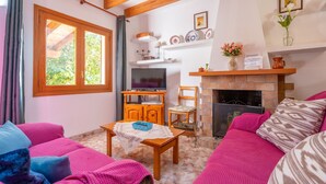 A cozy living room with a wooden ceiling, a fireplace, a TV, and a sofa with pink cushions. - Ca Na Xisca Pollen a (Pollenca)