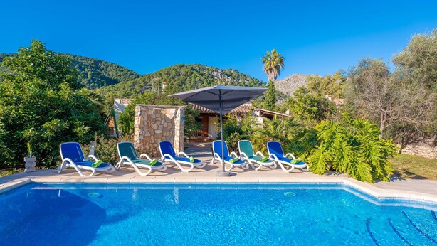 A swimming pool with lounge chairs and a stone structure in the background. - Ca Na Xisca Pollen a (Pollenca)