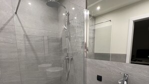 A modern bathroom with a glass-enclosed shower, a white sink, and a large mirror.